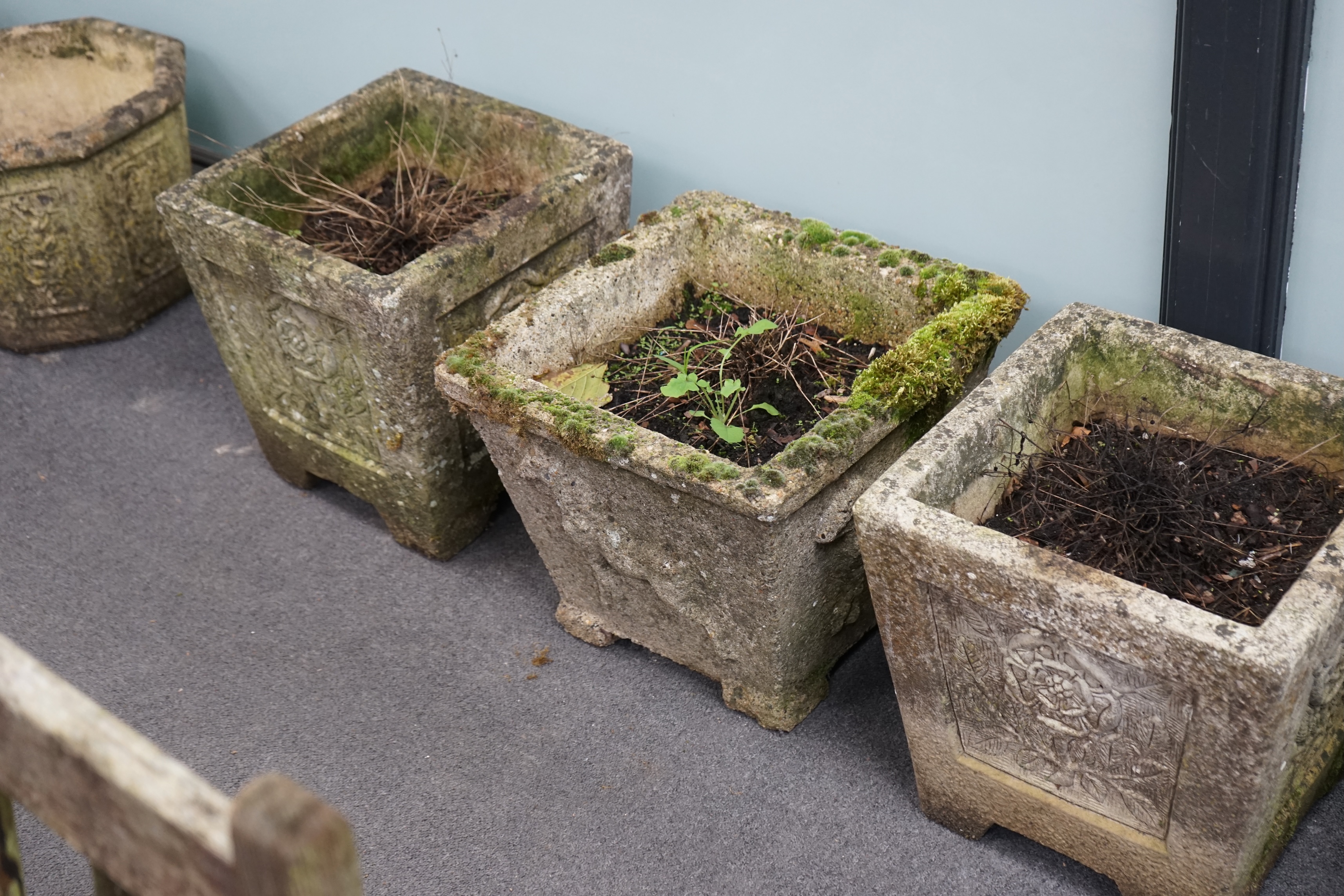 A set of three reconstituted stone garden planters, decorated with Tudor roses, 36cm sq., 37cm high, and a single square planter moulded in relief with a horse